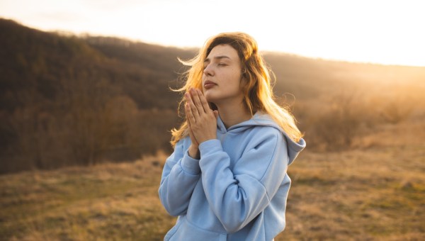 kobieta modli się na otwartej przestrzeni o zachodzie słońca