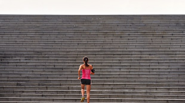 sporty woman running up stairs