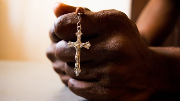 Nigerian man prays, hands, rosary
