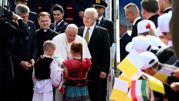 Pope Francis is greeted by children wearing traditional Hungarian dresses after he arrived