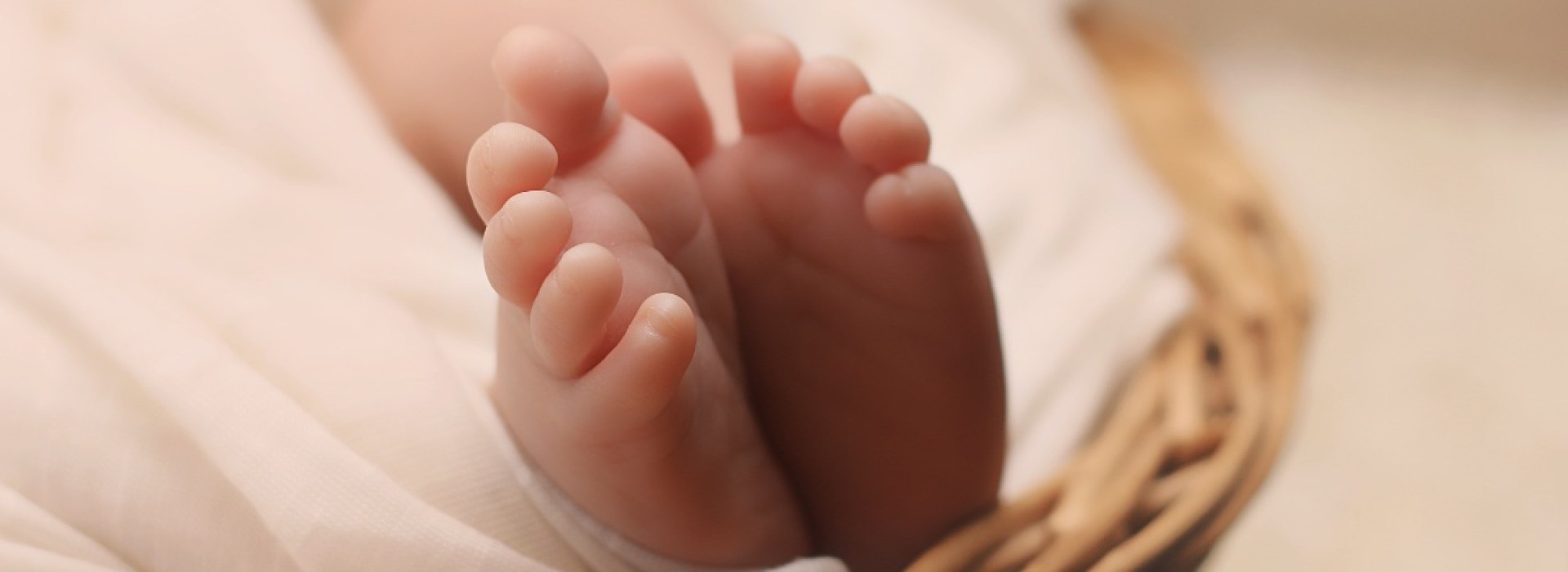 The feet of a newborn baby sticking out from blankets in a basket