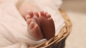 The feet of a newborn baby sticking out from blankets in a basket