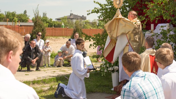 Priest holds up monstrance in outdoors Eucharistic procession