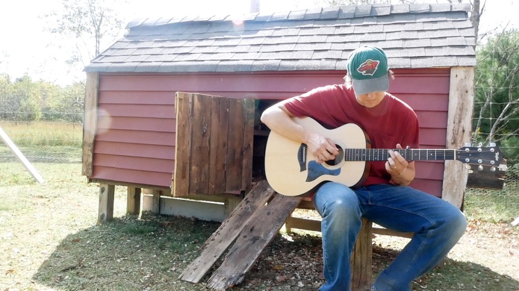 Jacob Rudd plays guitar by the chicken coop