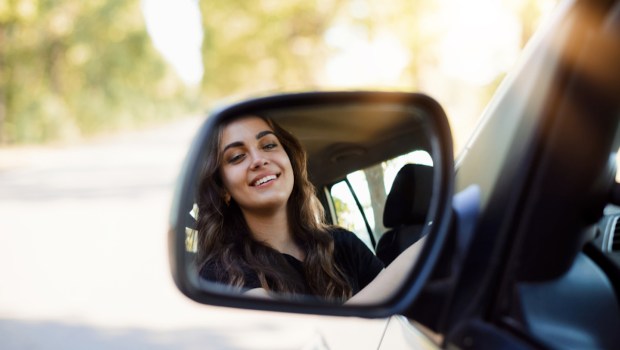 Mulher olhando no retrovisor do carro