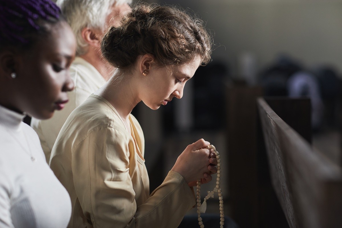 Young adult Catholic praying in church
