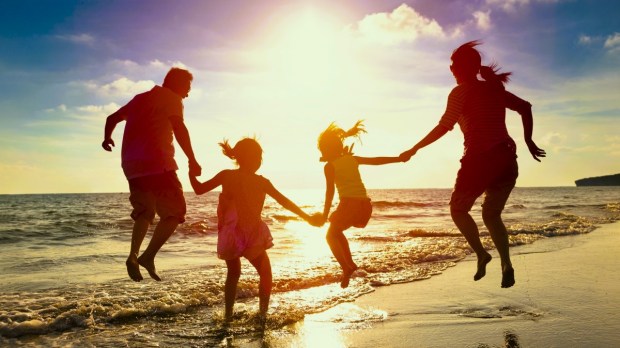 Family jumping together at the beach at sunset