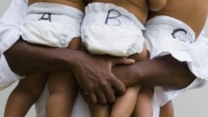 Baby triplets labeled ABC being held by dad