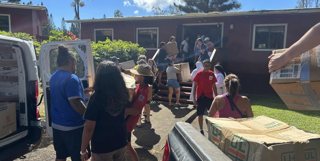 Volunteers unload supplies as Sacred Hearts School prepares to open in its new location.