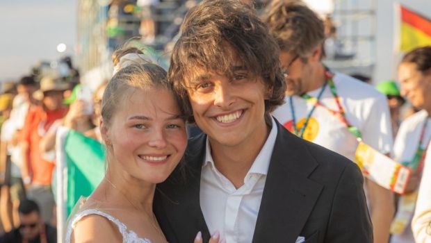 A Polish couple wearing a wedding dress and a suit smile at the camera at World Youth Day 2023 in Lisbon