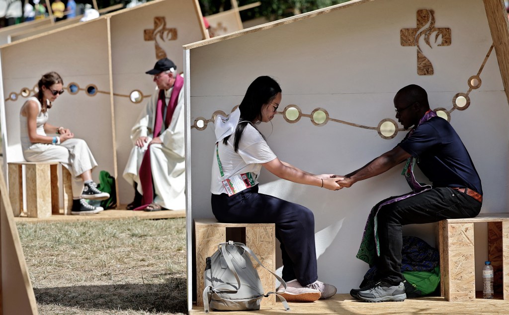 Pilgrims confess in an open confessionals area in Belem, Lisbon, during the World Youth Day