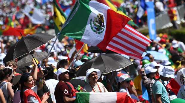 Pilgrims wave flags as they arrive before the start of the welcoming ceremony of World Youth Day