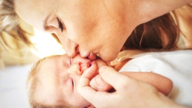 Mother kisses newborn baby