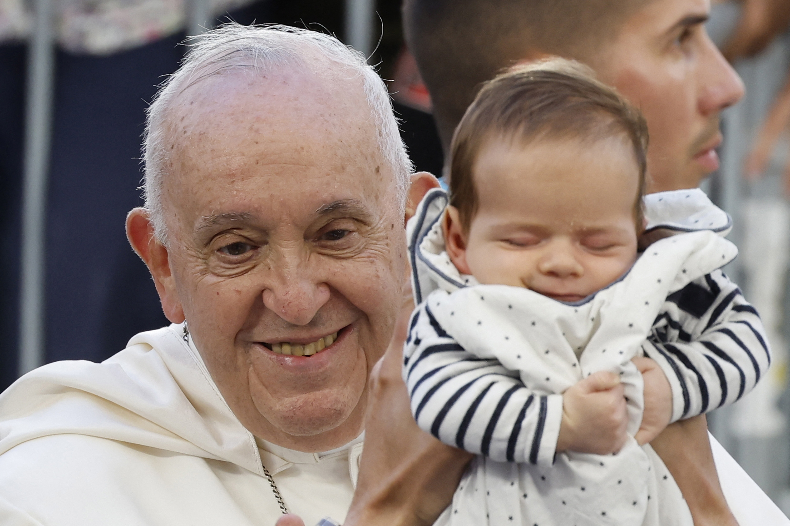 A baby is held up to Pope Francis as he arrives at the Velodrome stadium in his popemobile for a mass in the southern port city of Marseille