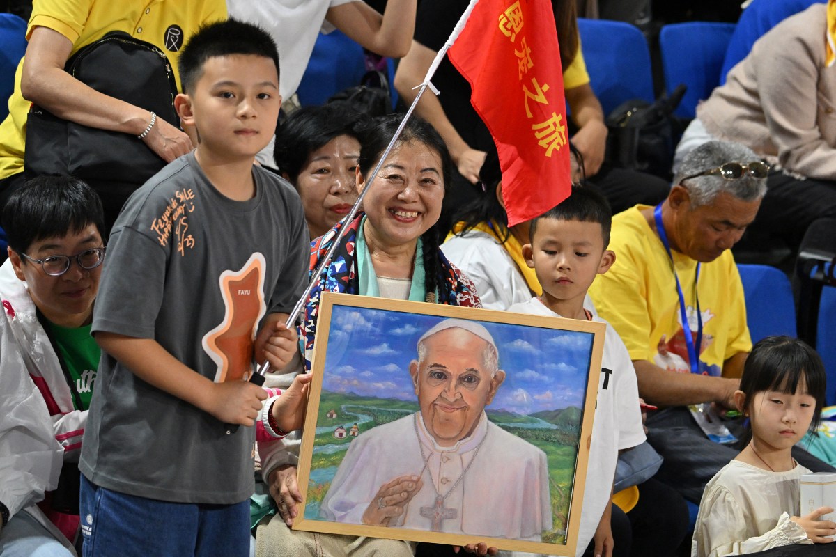 A woman holds an artwork portrait of Pope Francis as the faithful gather to attend mass led by the pope at the Steppe Arena in Ulaanbaatar