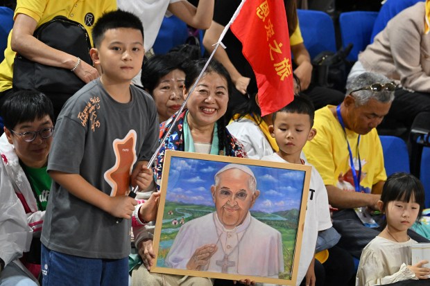 A woman holds an artwork portrait of Pope Francis as the faithful gather to attend mass led by the pope at the Steppe Arena in Ulaanbaatar