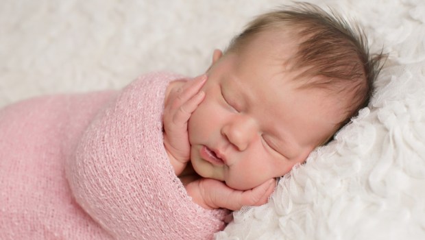 Close up of baby girl with her hands on her cheeks