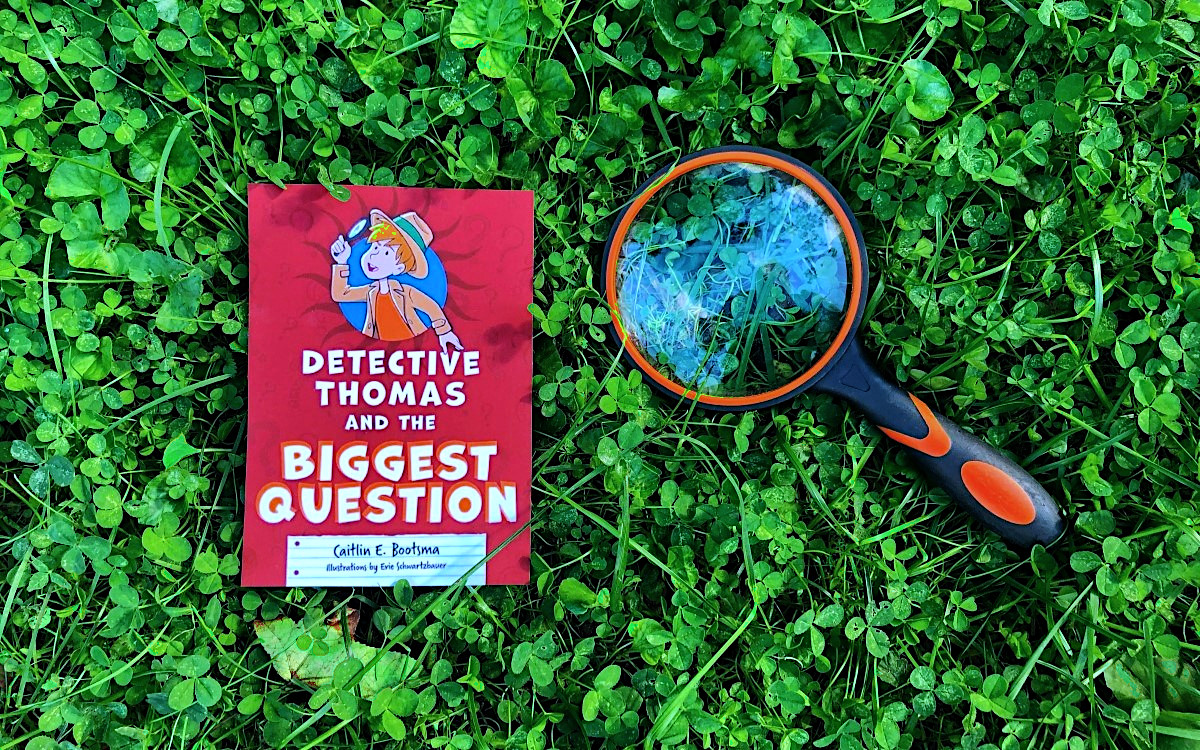 Kids book "Detective Thomas and the Really Big Question" on lawn with magnifying glass