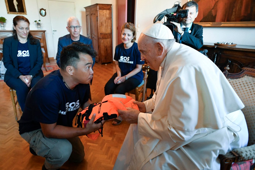 Pope Francis receiving a life jacket from a member of SOS Mediterranee a European NGO that rescue migrants at sea
