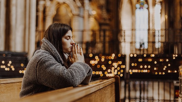 Woman praying in church with candles