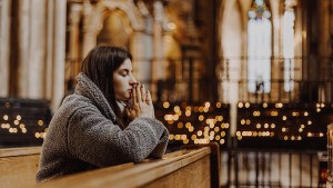 Woman praying in church with candles