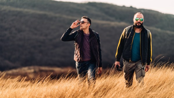 Dwóch mężczyzn idzie po trawiastym zboczu góry