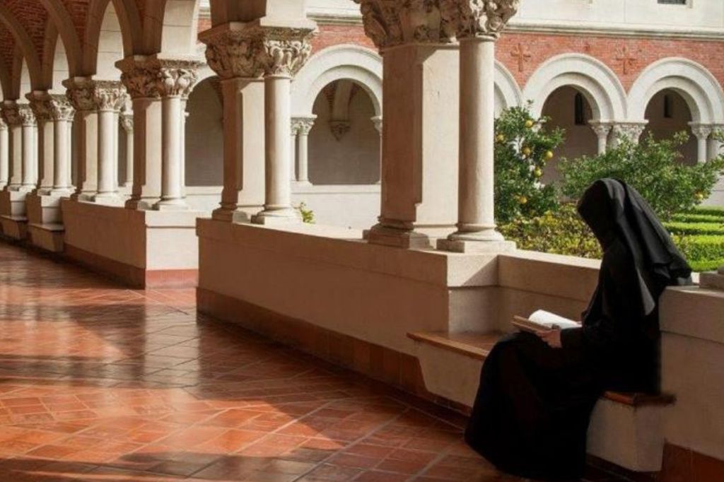 Nun praying in the cloister of a monastery