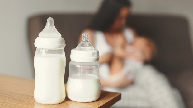 Mom nursing baby with bottles of milk in the foreground