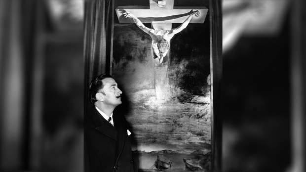 Spanish painter Salvador Dali posing next to his masterpiece Christ of St. John of the Cross