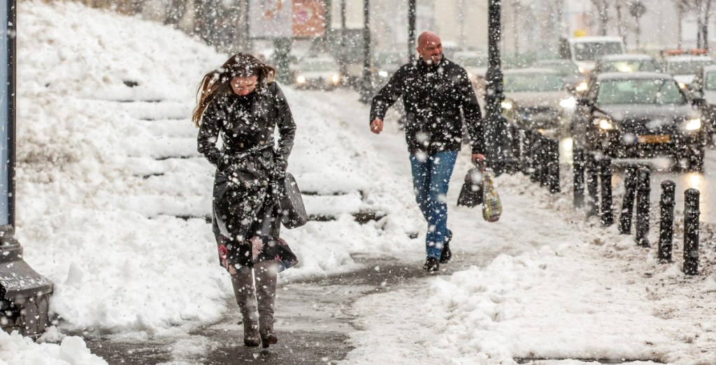 A woman and a man walking to work in the snow in the city