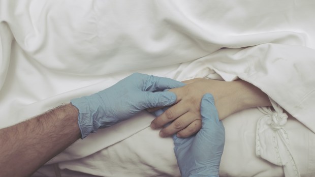 Medical professional holds hand of dying patient