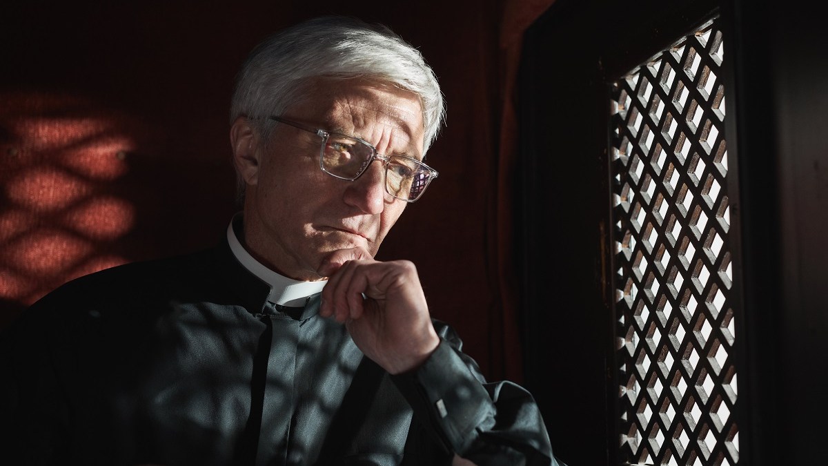 Serious priest in confessional