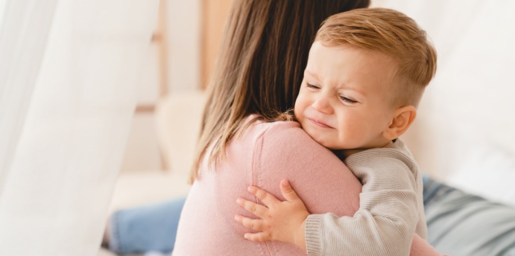 Upset boy toddler hugs mom