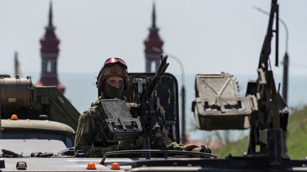 Russian soldier with church in background, Berdyansk, 2022