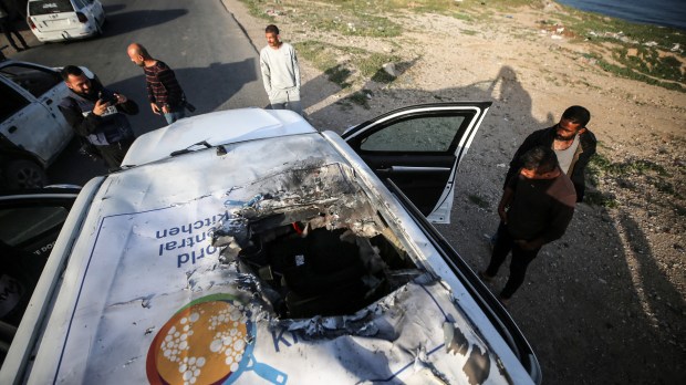 Palestinians are standing next to a vehicle in Deir Al-Balah, in the central Gaza Strip, on April 2, 2024