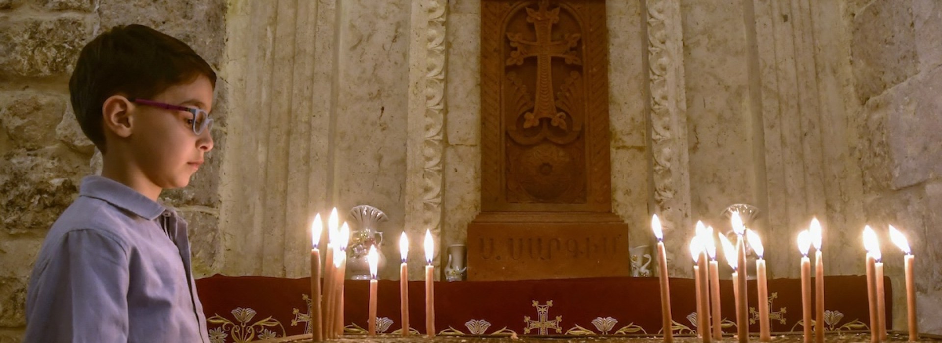 Syrian christian boy lights candle in Aleppo church