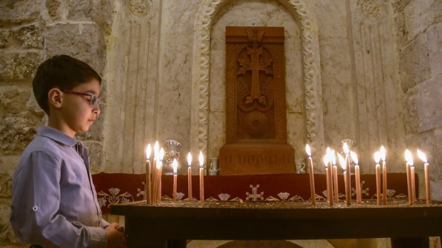 Syrian christian boy lights candle in Aleppo church