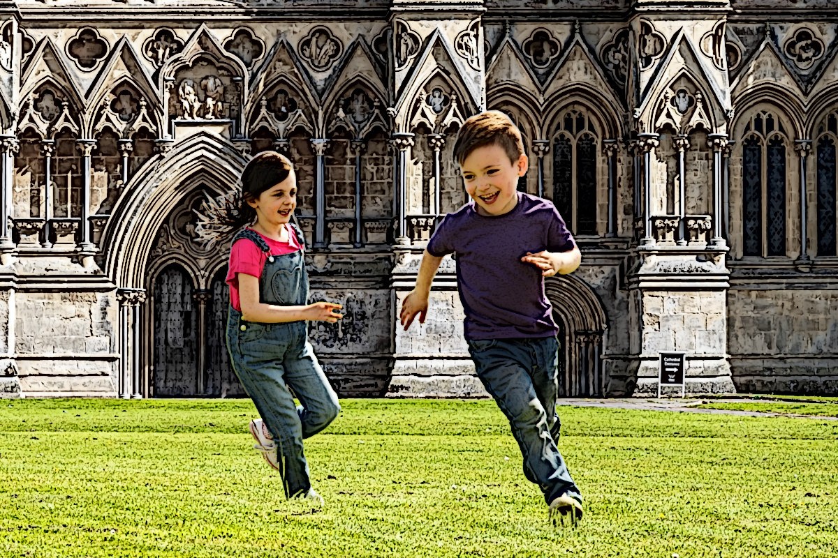 Kids running on lawn outside cathedral