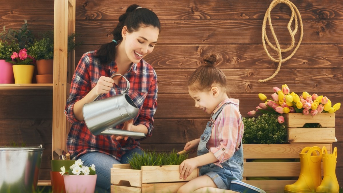 Mom watering plant with daughter