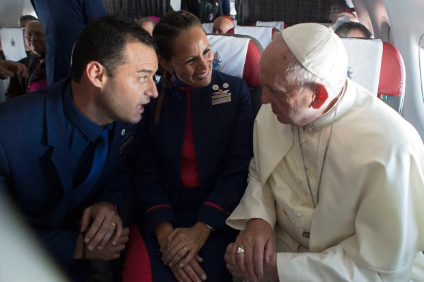 Pope Francis (R) taking to Latam airline flight attendants Paula Podest (C) and Carlos Ciuffardi on the plane