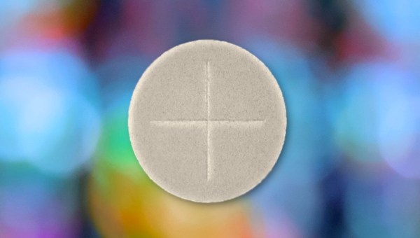 Holy communion host against blurred stained glass window