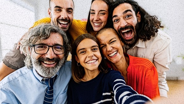 Family with adult aged siblings poses for selfie.