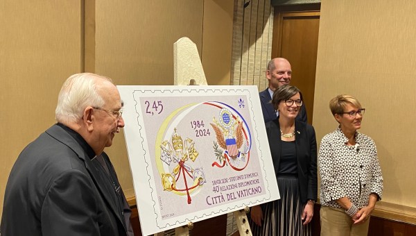 Cardinal Fernandez Alzaga and US embassy Chargé d'Affaires Laura Hochla stand by a commemorative stamp to celebrate 40 years of US-Holy See diplomatic relations.