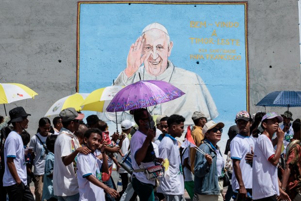 Catholic faithful walk in front of a graffiti of Pope Francis before a mass, which is expected to attract more than half of the country's 1.3 million people, in Dili on September 10, 2024.