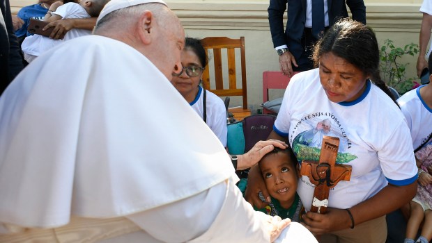 Pope Francis (L) blesses a child during a visit for children with disabilities at the Irmas Alma school in Dili.