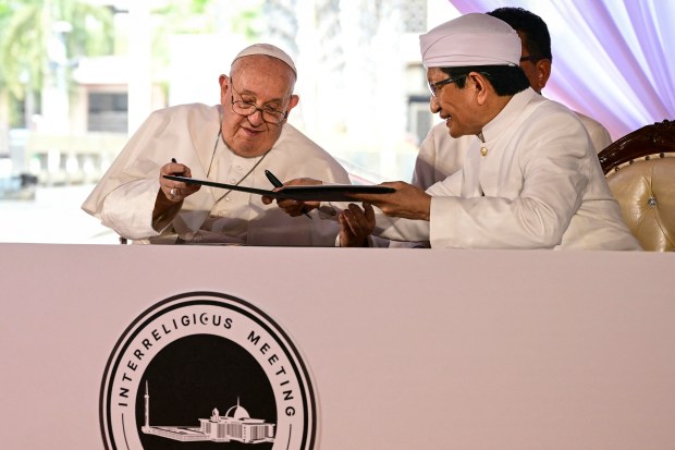 Pope Francis (L) and Grand Imam of Istiqlal Mosque Nasaruddin Umar exchange documents as they sign a declaration during an interreligious meeting with religious leaders at the Istiqlal Mosque in Jakarta on September 5, 2024.