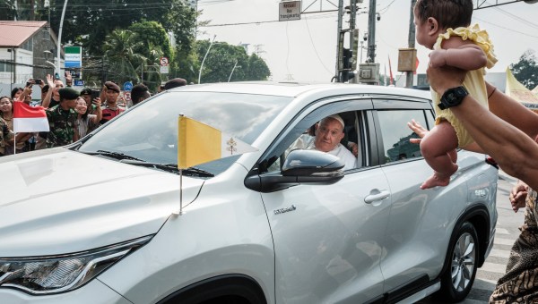A man holds his baby for Pope Francis to bless as he leaves for Jakarta's Soekarno-Hatta International Airport ahead of his departure to Papua New Guinea's capital Port Moresby on September 6, 2024.