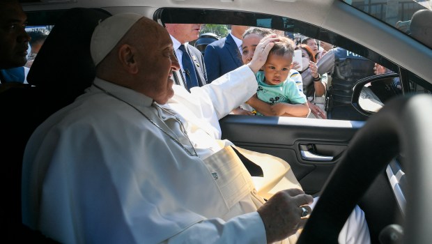 Pope Francis blesses a child as he arrives for a meeting with beneficiaries from charitable organizations, during his apostolic visit to Asia, at Indonesian Bishops' Conference headquarters in Jakarta.