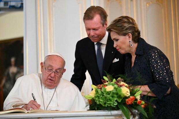 Pope Francis signs the book of honor next to Grand Duke Henri of Luxembourg and his wife Grand Duchess Maria Teresa at the Grand ducal palace in Luxembourg