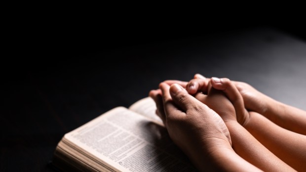 Bible in hand, a Christian prays with faith and hope